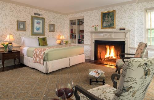 Cozy bedroom with a fireplace, a large bed, armchair, and floral wallpaper, creating a warm, inviting atmosphere.