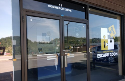 Entrance to an escape room facility with large glass doors and a sign displaying "Morgantown Escape Room."