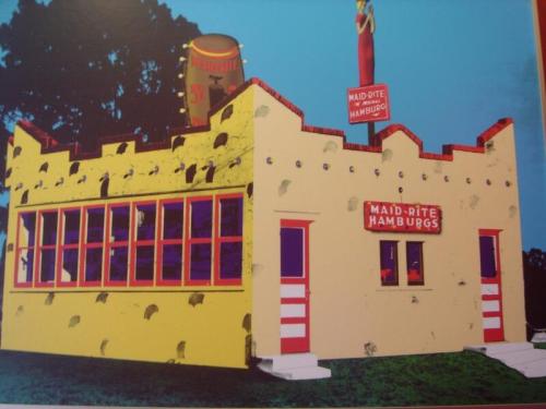 A colorful, retro-style hamburger restaurant with a yellow exterior and large sign reading "Maid-Rite Hamburgs."