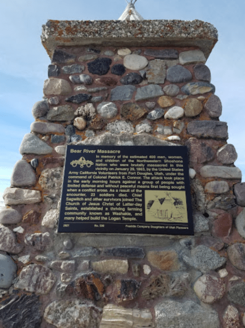 A stone monument with a plaque commemorating the Bear River Massacre and its historical significance.