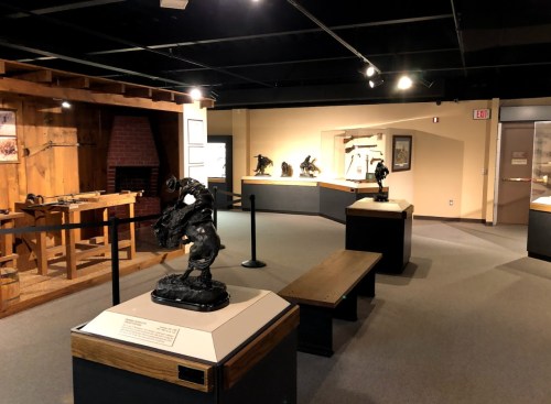 A museum interior featuring sculptures, display cases, and wooden exhibits in a well-lit space.