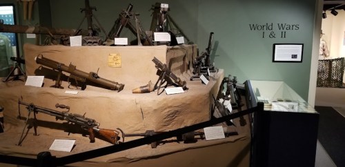 Display of various firearms and weapons from World Wars I and II in a museum setting.