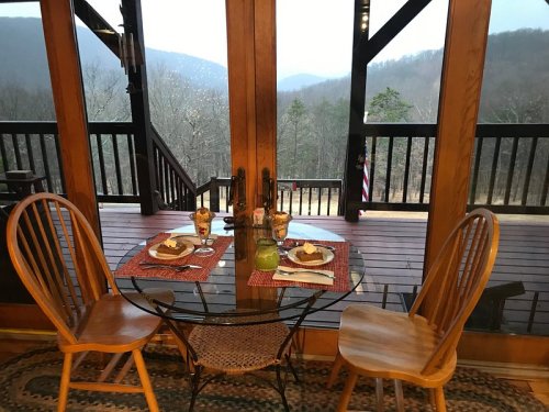 A cozy dining setup with two chairs and a table, overlooking a scenic mountain view through large windows.
