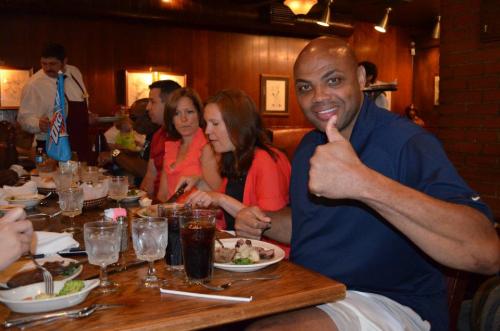 A group dining at a restaurant, with a man giving a thumbs up and enjoying his meal.