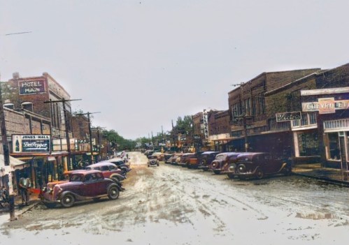 A vintage street scene with classic cars, shops, and a hotel, showcasing a nostalgic small-town atmosphere.
