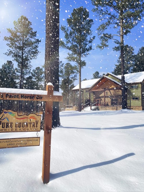 A snowy scene featuring a cabin surrounded by tall pine trees, with a sign for "Pine Country Hideaway."