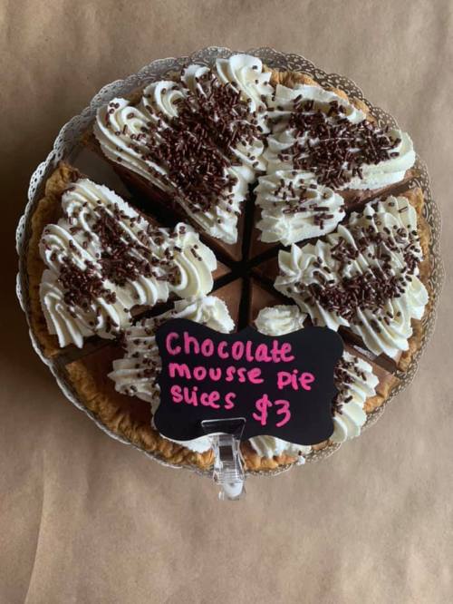 A chocolate mousse pie sliced into pieces, topped with whipped cream and chocolate shavings, priced at $3.