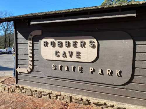 Sign for Robbers Cave State Park, featuring wooden letters on a rustic building.