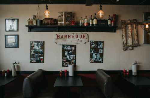 Cozy restaurant interior featuring a barbecue sign, vintage decor, and tables with condiments.