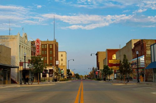 A quiet downtown street with historic buildings, a theater sign, and clear blue skies.