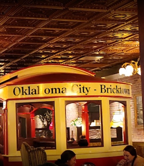 A colorful train-themed interior in a restaurant, featuring "Oklahoma City - Bricktown" signage. Cozy atmosphere.