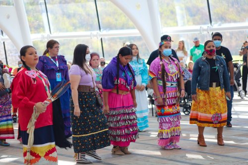 A group of women in traditional attire participate in a cultural event, showcasing vibrant colors and patterns.