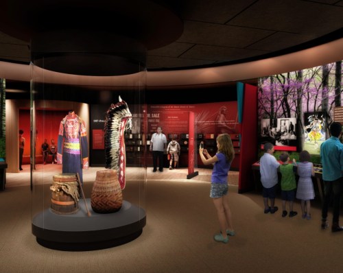 A museum exhibit featuring colorful artifacts, with visitors exploring and taking photos in a circular display area.