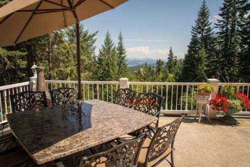 A patio with a marble table and chairs, surrounded by trees and a scenic mountain view in the background.