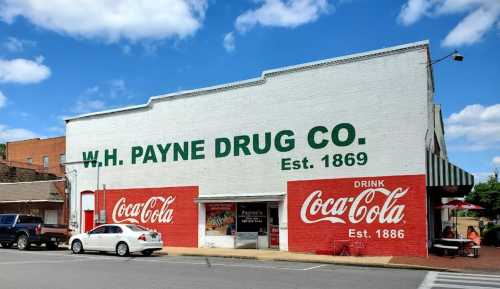 Historic W.H. Payne Drug Co. building with Coca-Cola advertisements, established 1869, under a blue sky.