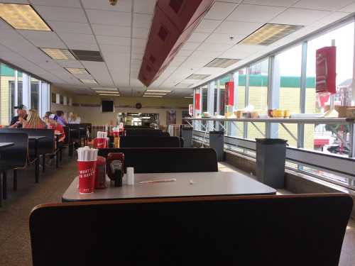 A spacious diner interior with empty tables, condiments on each table, and large windows letting in natural light.