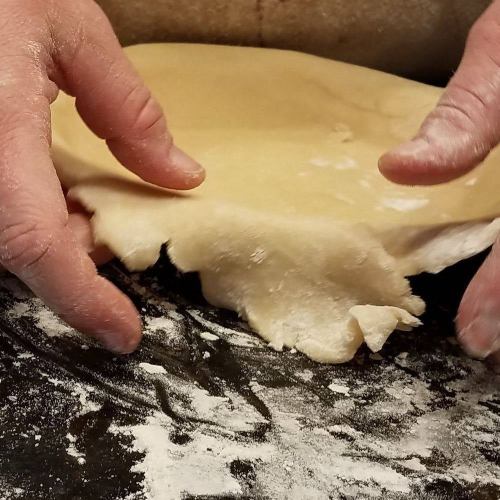 A close-up of hands working with dough on a floured surface, preparing it for baking.