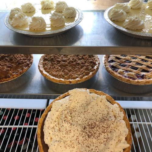 A display of various pies and desserts, including cream pies, fruit pies, and a chocolate-topped pie.