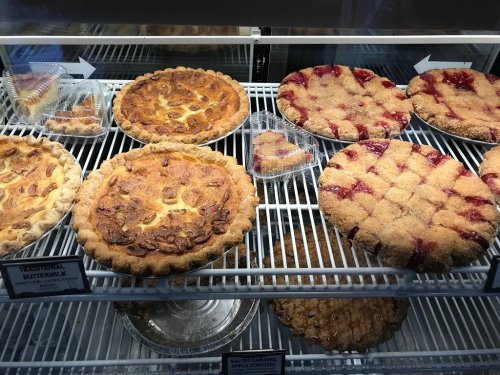 A display case filled with various pies, including buttermilk, fruit, and crumb-topped varieties.