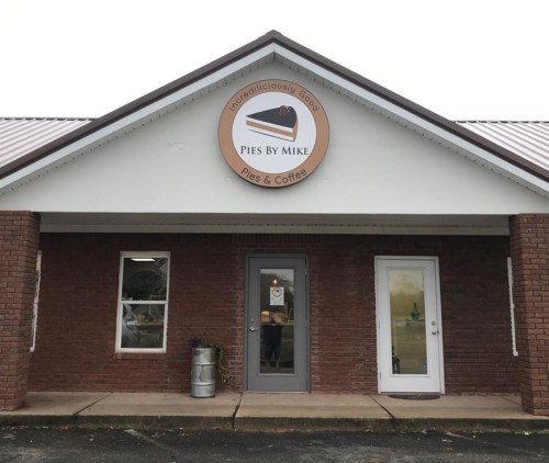 Exterior of a brick building with a sign reading "Pies By Mike" and a logo featuring a pie.