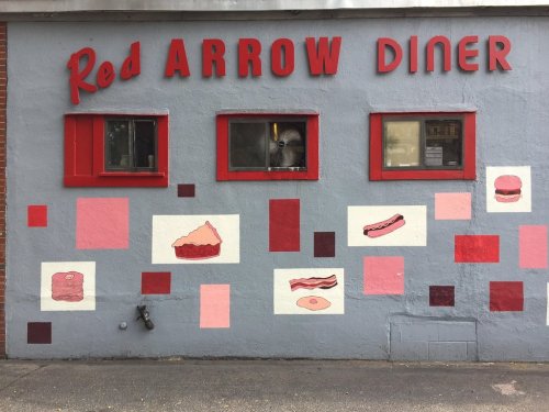 A colorful diner exterior featuring the name "Red Arrow Diner" and food-themed murals on the wall.