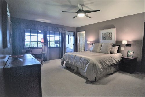 Cozy bedroom with a large bed, nightstands, a dresser, and a window overlooking a scenic view. Soft lighting and decor.