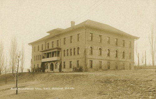Historic sepia-toned photo of a large brick building with arched windows, labeled "1033 Riddebauch Hall, W. of Moscow, Idaho."