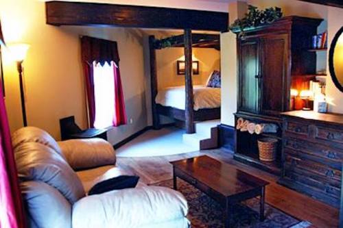 Cozy living area with a sofa, wooden coffee table, and a view of a bedroom with a bed and decorative elements.