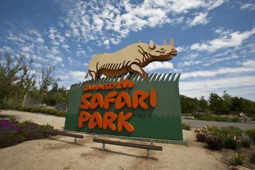 Sign for San Diego Zoo Safari Park featuring a rhino design, surrounded by greenery and a blue sky.