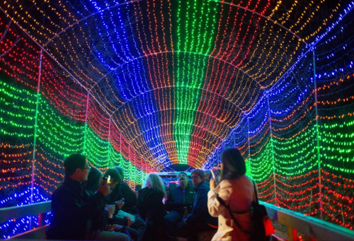 A colorful tunnel of lights with people sitting inside, enjoying the vibrant display.