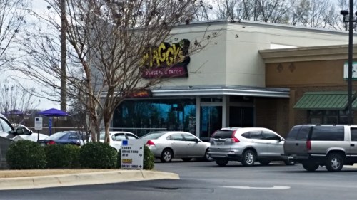 A restaurant named "Shaggy's" with a parking lot filled with cars, surrounded by trees and a cloudy sky.