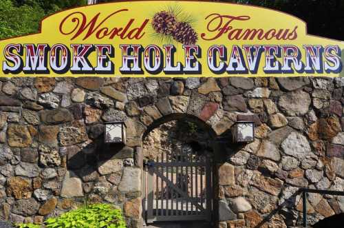 Sign for "World Famous Smoke Hole Caverns" above a stone archway, surrounded by greenery.