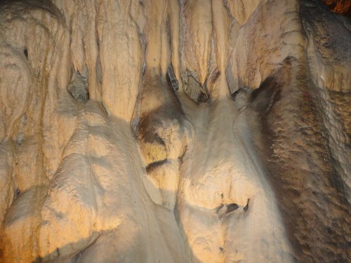 Close-up of textured cave wall with natural formations and shadows, showcasing unique geological features.