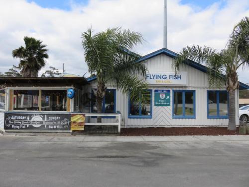A coastal restaurant named "Flying Fish" with palm trees and a sign advertising weekend specials.