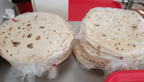 Stacks of wrapped tortillas on a tray, ready for serving.