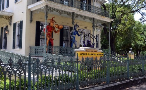 Exterior of the Mobile Carnival Museum, featuring colorful jester murals and ornate ironwork.