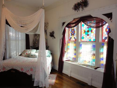 A cozy bedroom featuring a canopy bed and colorful stained glass windows.