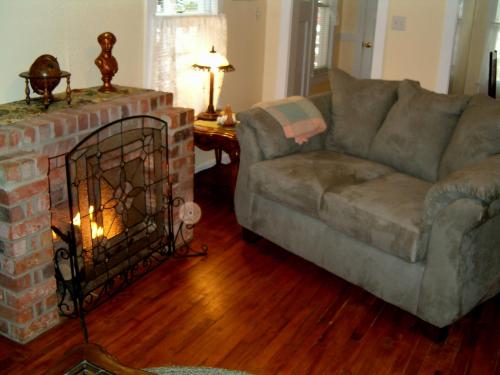 Cozy living room with a brick fireplace, a plush gray couch, and warm lighting from lamps.