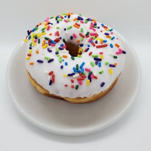 A frosted donut with colorful sprinkles on a white plate.