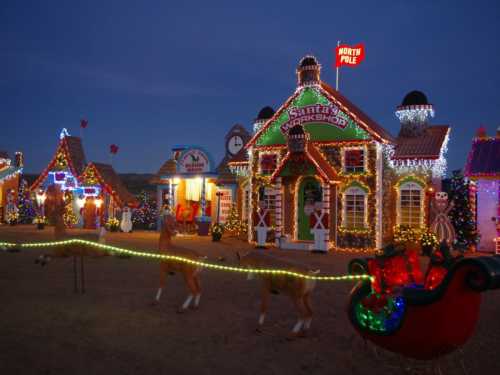 Colorful holiday scene featuring a lit-up Santa's workshop, reindeer, and a sleigh against a twilight sky.