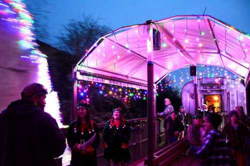 A festive train platform decorated with colorful lights, featuring people enjoying the holiday atmosphere.