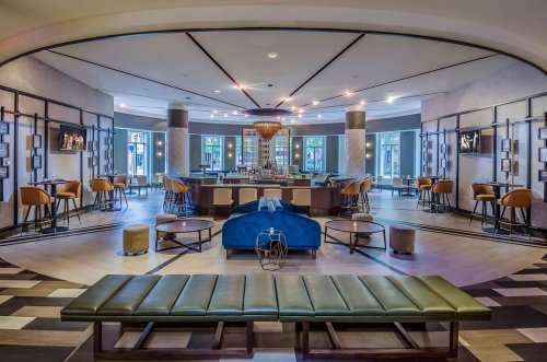 Modern lounge with a bar, stylish seating, and large windows, creating a welcoming atmosphere.
