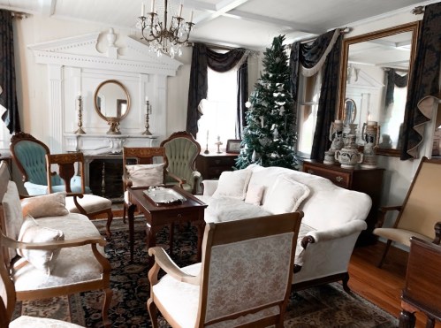 A cozy living room with elegant furniture, a Christmas tree, and a decorative fireplace.