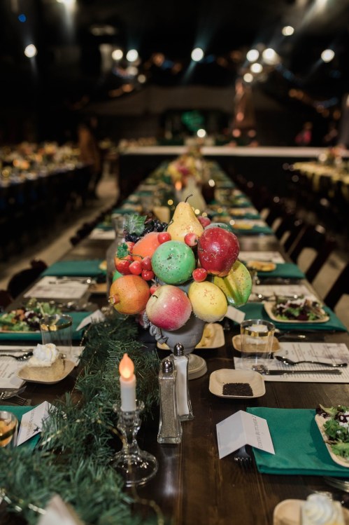 A long dining table set with plates and a colorful fruit centerpiece, surrounded by festive decorations.