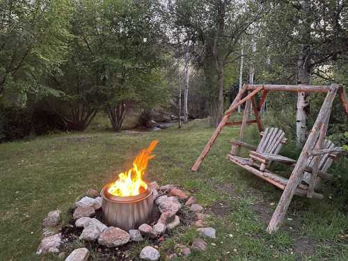 A cozy outdoor scene featuring a fire pit surrounded by stones and a wooden swing set in a lush green setting.