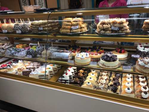 A display case filled with a variety of colorful desserts, including cakes, pastries, and sweets.