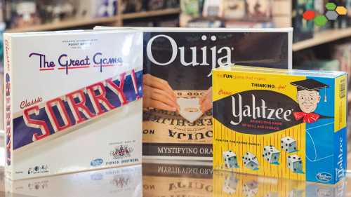 Three board games displayed: "Sorry!", "Ouija", and "Yahtzee", showcasing colorful boxes on a wooden surface.