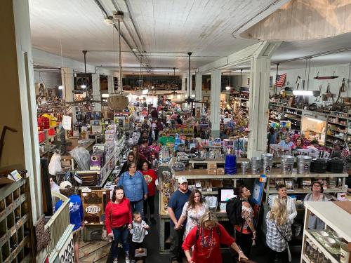 A bustling antique store filled with people browsing various items and displays.