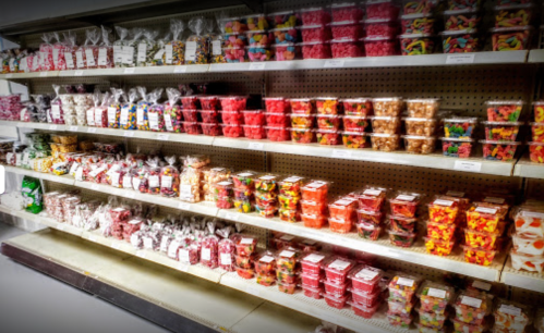 A colorful display of various candies in clear containers on shelves, showcasing a wide assortment of sweets.