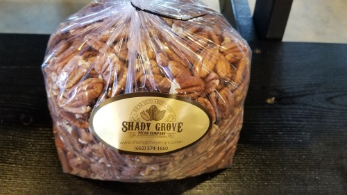 A clear bag filled with pecans, labeled "Shady Grove Pecan Company" with contact information and a logo.